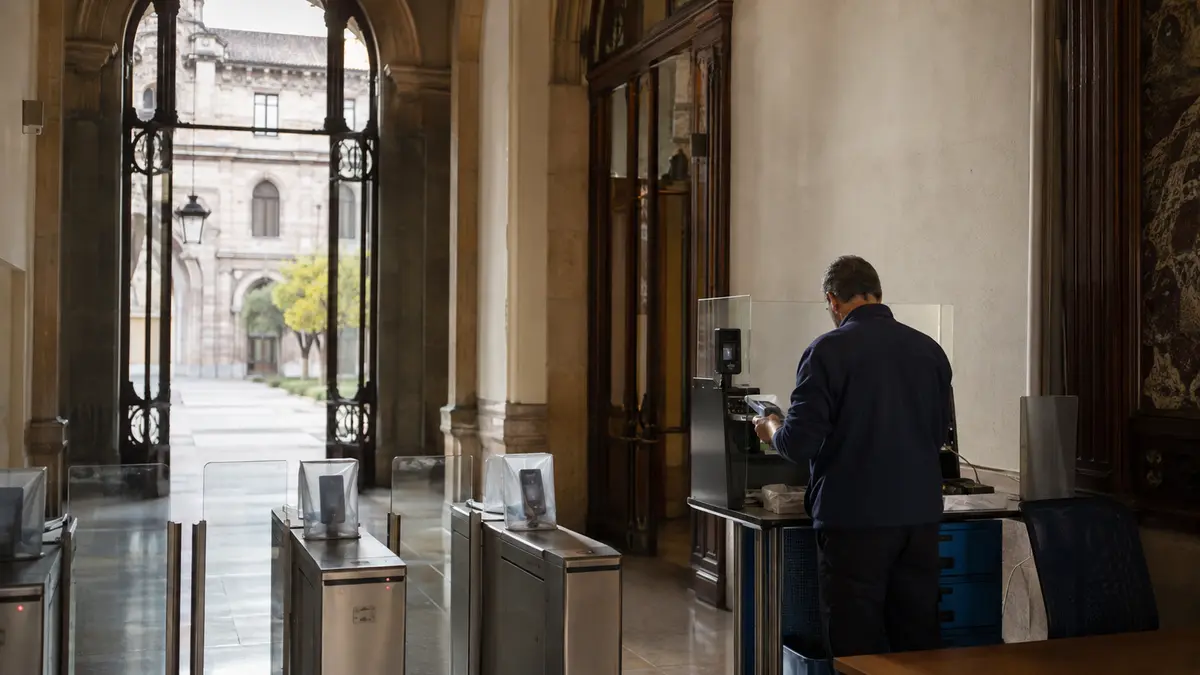 Técnico renueva credenciales junto a controles de acceso de un edificio universitario histórico